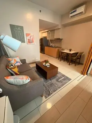 a living room with a couch and a table at One Bedroom with Netflix at Uptown Residences, BGC, Taguig in Manila
