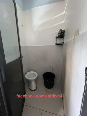 a bathroom with a toilet and a plant on a shelf at Studio in the 2nd floor Transient Room with two wallfan in Manila