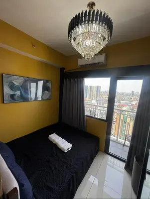 a bedroom with a black bed and a chandelier at David's Cozy Home in Manila