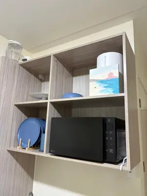 a kitchen cabinet with a microwave and some dishes at Faith Studio Cubao in Manila