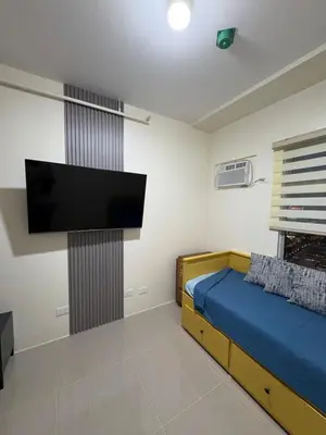 a bedroom with a bed and a flat screen tv at Faith Studio Cubao in Manila
