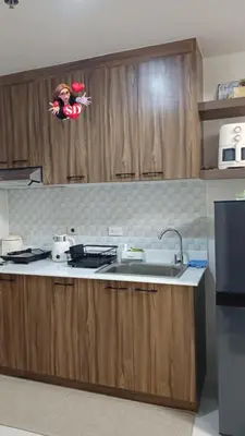 a kitchen with wooden cabinets and a counter top with a sink at Condotels Near Sucat Skyway in Manila