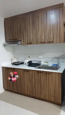a kitchen with wooden cabinets and a sink at Condotels Near Sucat Skyway in Manila