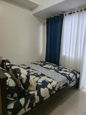 a bed in a room with blue curtains at J&W Homestay in Manila
