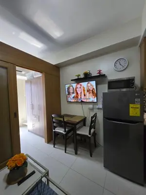 a kitchen with a table and a tv on the wall at J&W Homestay in Manila