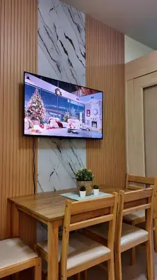 a television hanging on a wall with a wooden table at Sea Residence 1BR unit 5 to 10 min walk to MOA by Angels Cozy Corner in Manila
