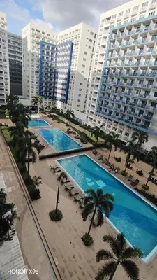 an overhead view of two pools with palm trees and buildings at Moa SEA RESIDENCE condotel in Manila