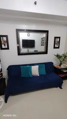 a blue couch in a living room with a mirror at Moa SEA RESIDENCE condotel in Manila