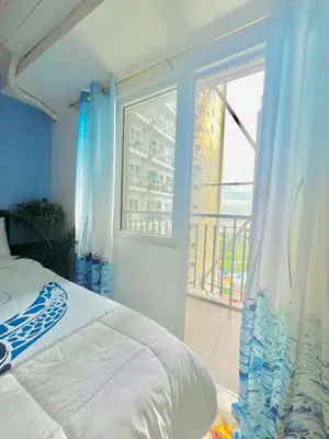 a bedroom with a bed and a window with a balcony at Cozy Condo with Balcony and Bay view plus PS4 at Taft Malate in Manila