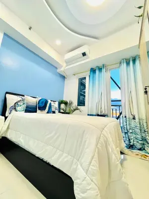 a bedroom with a large bed with blue walls at Cozy Condo with Balcony and Bay view plus PS4 at Taft Malate in Manila