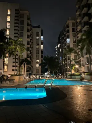 a swimming pool at night with tall buildings at One Palm Tree Villas-Hyuna Place Across Naia T3 Manila in Manila