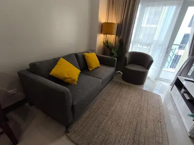 a living room with a grey couch with yellow pillows at Comfortable and Relaxing 1BR Unit in Manila