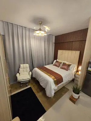a bedroom with a large bed and a chair at Skye Staycation 2 in Manila