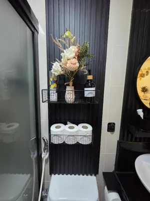 a bathroom with a toilet and a shelf with towels at Skye Staycation 2 in Manila