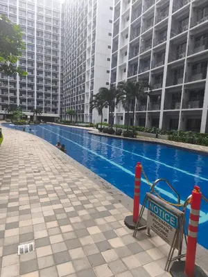a swimming pool in a building with tall buildings at MOA Staycation in Manila