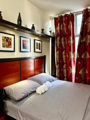 a bed in a bedroom with red curtains at Condo in Poblacion, Makati in Manila