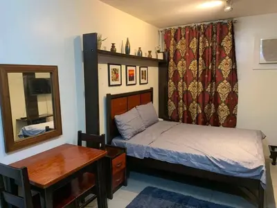 a bedroom with a bed and a desk and a mirror at Condo in Poblacion, Makati in Manila