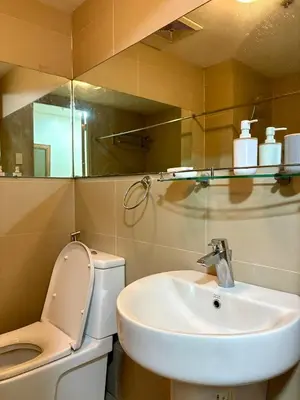 a bathroom with a sink and a toilet and a mirror at Condo in Poblacion, Makati in Manila