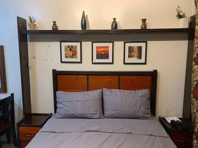 a bed with a wooden headboard with pictures on the wall at Condo in Poblacion, Makati in Manila
