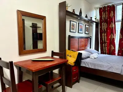 a bedroom with a bed and a table and a mirror at Condo in Poblacion, Makati in Manila