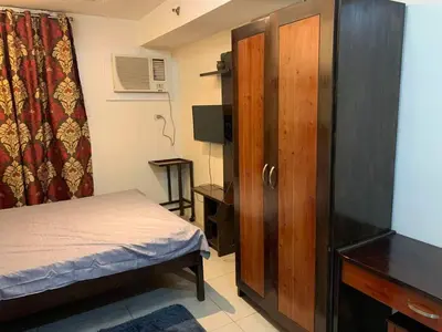 a small bedroom with a bed and a wooden cabinet at Condo in Poblacion, Makati in Manila