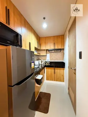 a kitchen with wooden cabinets and a stainless steel refrigerator at Eutopia Vista- 2 Bedroom Condo in SMDC Bloom in Manila