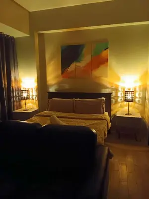 a bedroom with a bed with two lamps and a couch at Cluster 1 9N in Manila