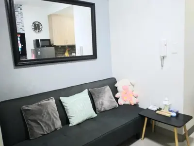 a black couch in a living room with a mirror at Shore Residences at Mall Of Asia Complex - by Staycation Empire in Manila