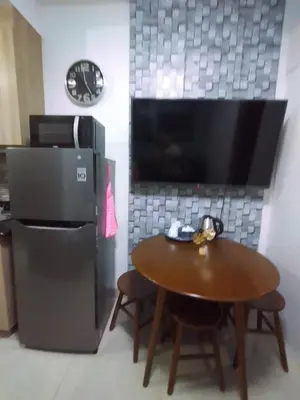 a kitchen with a table and a refrigerator at Shore Residences at Mall Of Asia Complex - by Staycation Empire in Manila