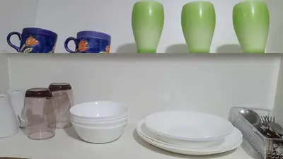 a shelf with plates and bowls and green vases at Shore Residences at Mall Of Asia Complex - by Staycation Empire in Manila