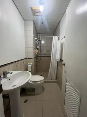 a bathroom with a sink and a toilet and a shower at Robinson's Place Residences, in Manila