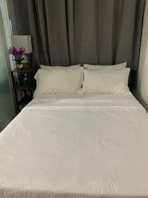 a large bed with white sheets and pillows at Robinson's Place Residences, in Manila