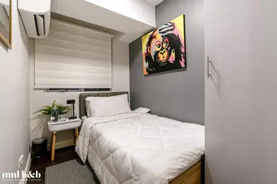 a small bedroom with a bed and a painting on the wall at UP TO 6 PAX! Spacious Loft 2 BR near High Street, BGC Fort Victoria The Fort, Taguig City in Manila