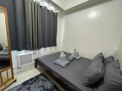 a small bedroom with a bed with a window at Sea Residences 1BR Stays - Near Airport & MOA Pasay in Manila