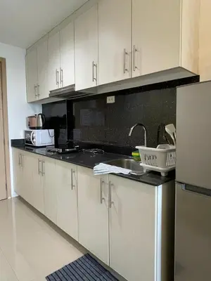 a kitchen with white cabinets and a sink and a refrigerator at Sea Residences 1BR Stays - Near Airport & MOA Pasay in Manila
