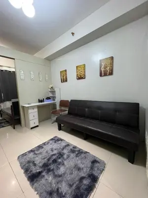 a living room with a black couch and a table at Sea Residences 1BR Stays - Near Airport & MOA Pasay in Manila