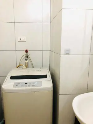 a small bathroom with a sink and a white stove at Hub Metro in makati 100west 1br with balcony in Manila
