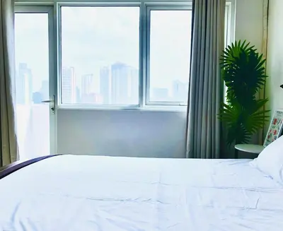 a bedroom with a white bed and a window at Hub Metro in makati 100west 1br with balcony in Manila