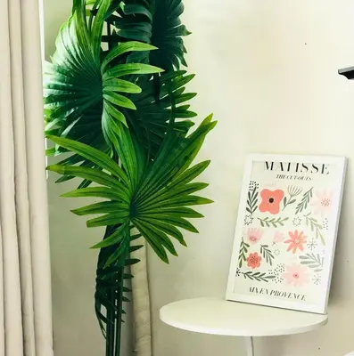 a plant in a room next to a table with a book at Hub Metro in makati 100west 1br with balcony in Manila