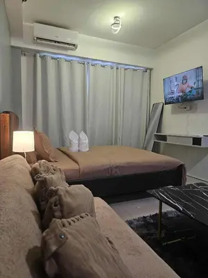 a living room with two beds and a tv at Shore Residences Sm mall of asia Marc in Manila