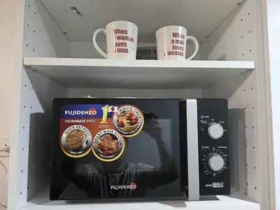 a shelf with a microwave and cups of coffee at Shore Residences Sm mall of asia Marc in Manila