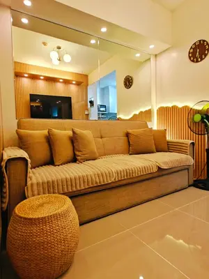 a living room with a brown couch and a mirror at Cozy Modern 1BR Light Residences with 55 inches 4K TV in Manila