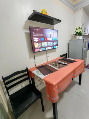 a desk with a tv and a chair in a room at Sea Residences near moa Glenda in Manila