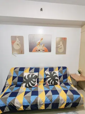 a couch in a living room with pictures on the wall at Sea Residences near moa Glenda in Manila
