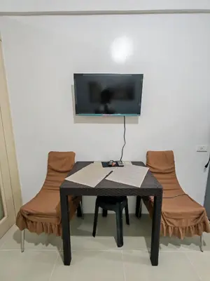 a table with chairs and a television on a wall at Sea Residences near moa Glenda in Manila