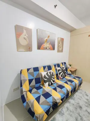 a living room with a couch and some pictures on the wall at Sea Residences near moa Glenda in Manila