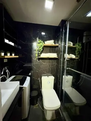 a bathroom with a toilet and a sink and a shower at Cozy Sunset Condo Thompson Stay in Manila