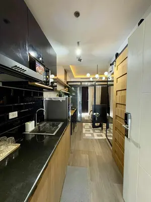 a kitchen with a black counter top and wooden cabinets at Cozy Sunset Condo Thompson Stay in Manila