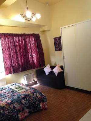 a bedroom with a bed and a couch and a window at Studio Condominium near the US Embassy in Manila in Manila