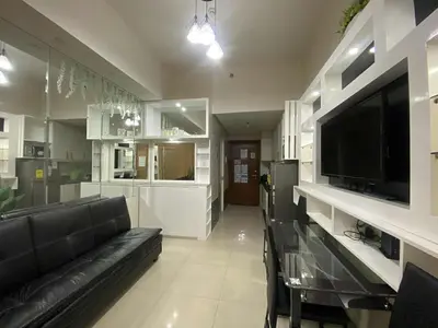 a living room with a black couch and a television at Shell Residences Mall of asia Pham in Manila